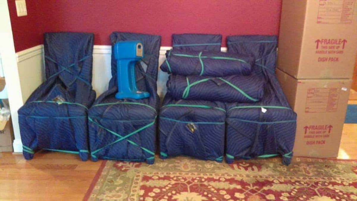 Dining chairs wrapped in moving blankets next to Fragile boxes